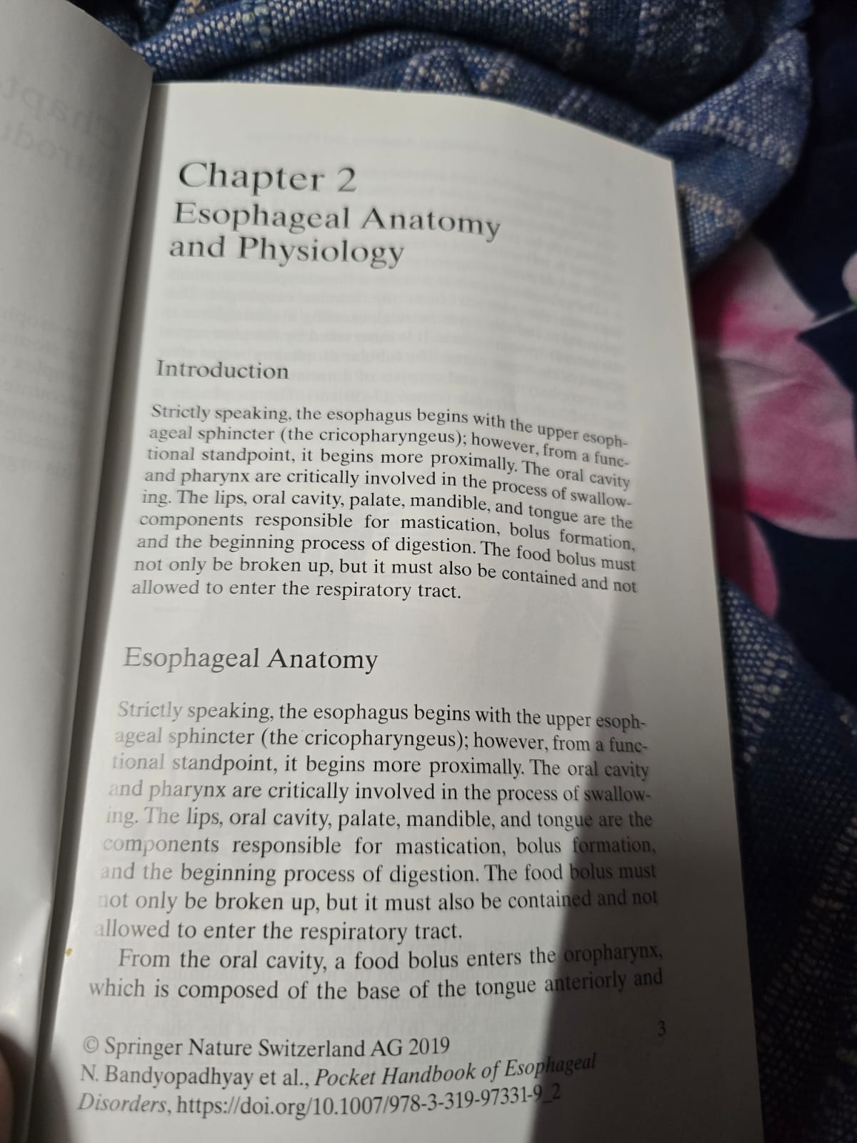 Phone photo of an open medical textbook chapter in uneven room light